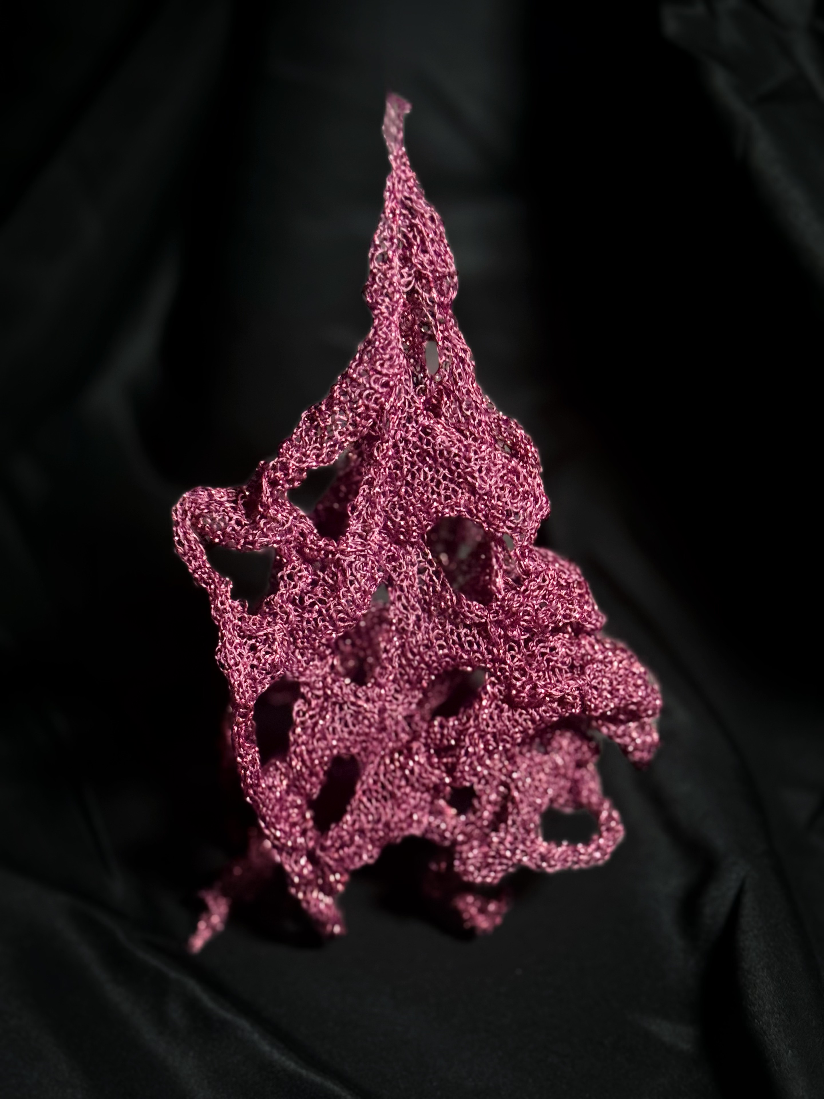 Purple-red knitted sample photographed against black fabric