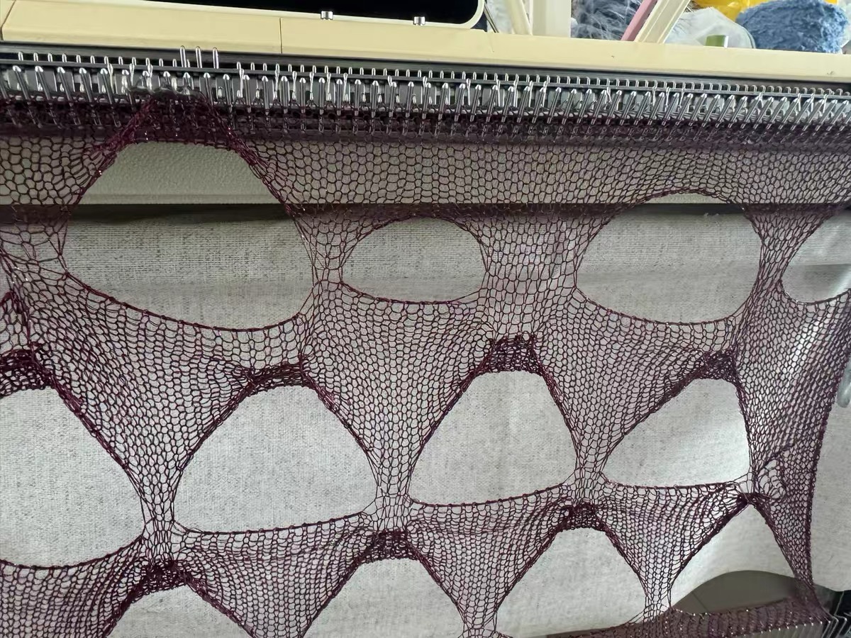 Open knitted textile held on Brother KH881 needles